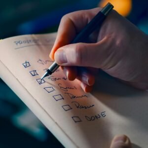Close-up of a hand writing a checklist in a notebook, symbolizing productivity and organization.
