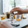 Detailed view of hands adding dried botanicals to a glass beaker in a lab setting.