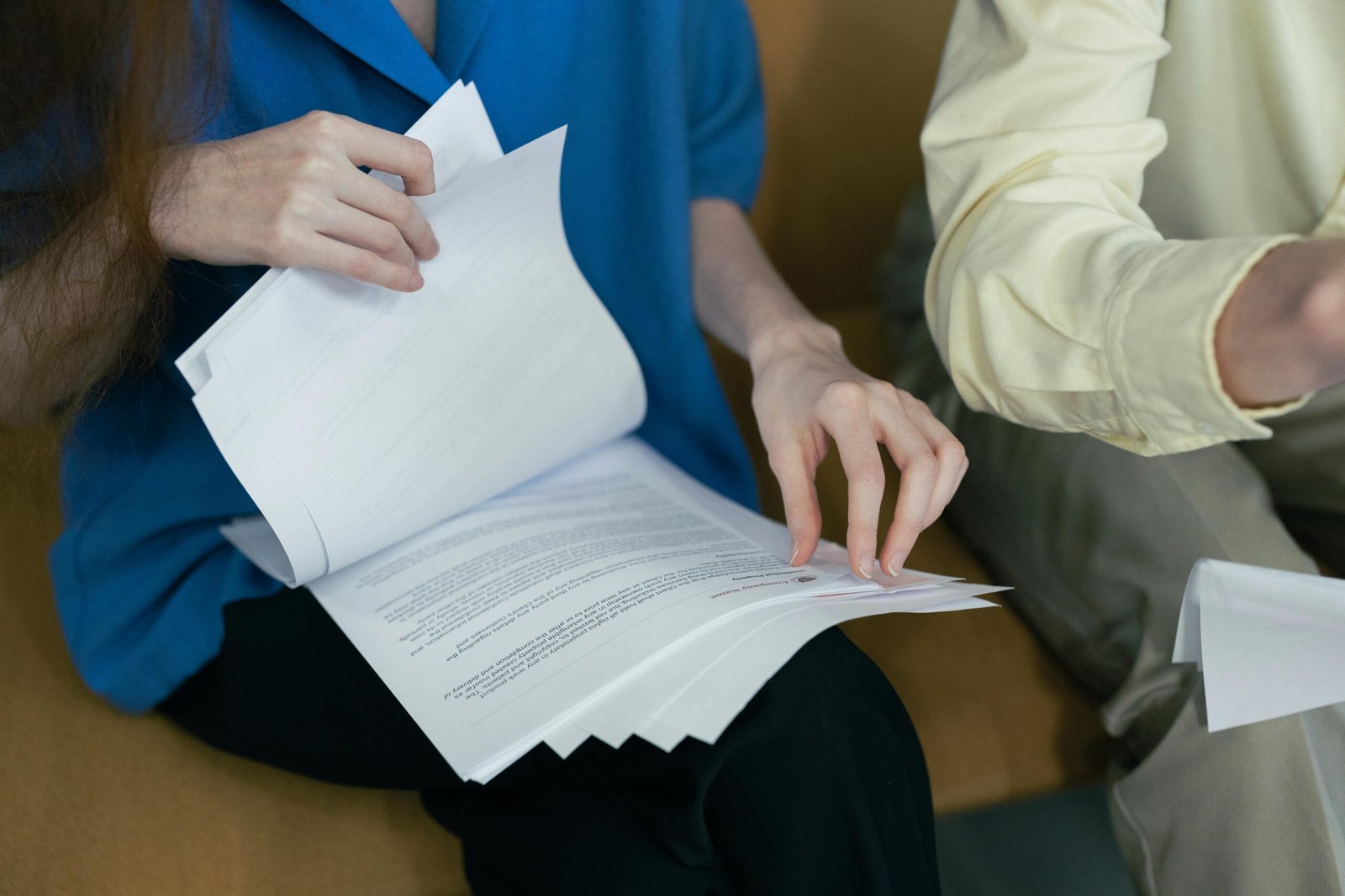 pexels photo 8453827 8453827 People in professional attire reviewing important documents together on a sofa.