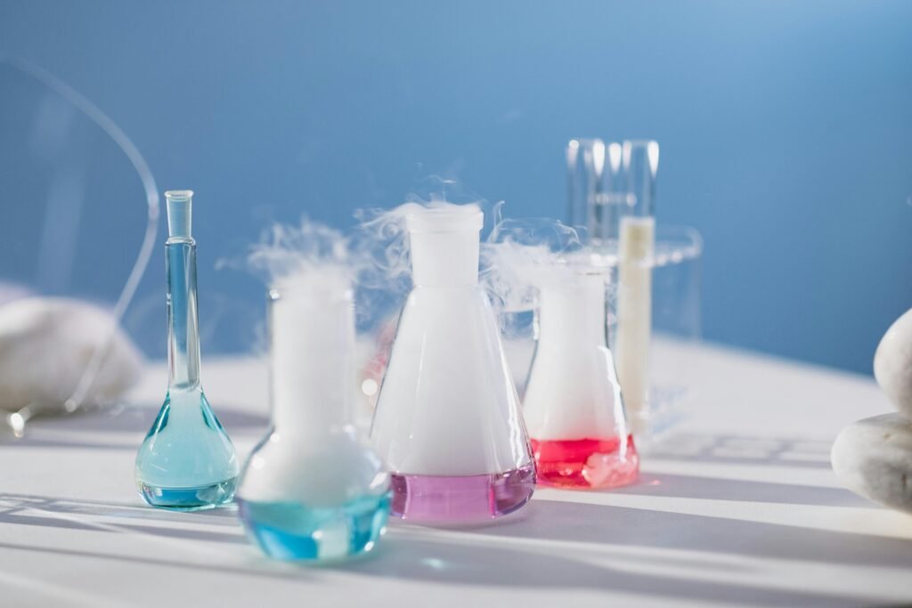 Brightly colored laboratory flasks emitting steam on a table, showcasing scientific exploration.