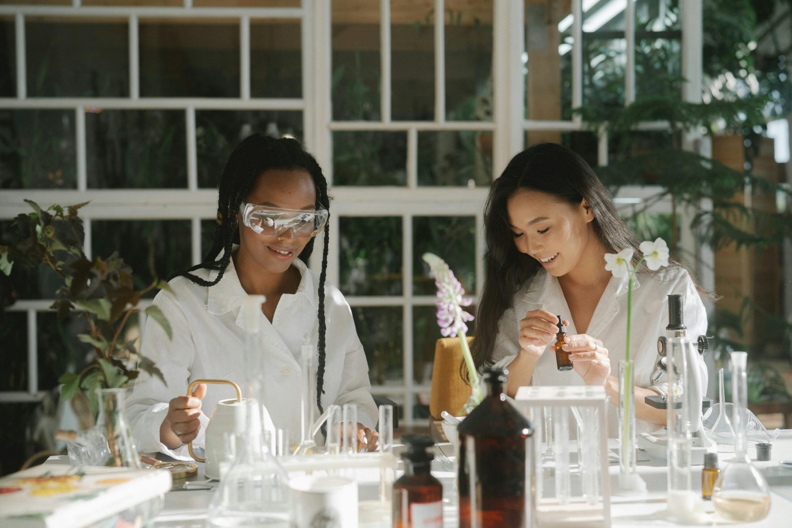 zipwp image 8514600 Two young botanists working with plants and chemicals in a sunlit lab.